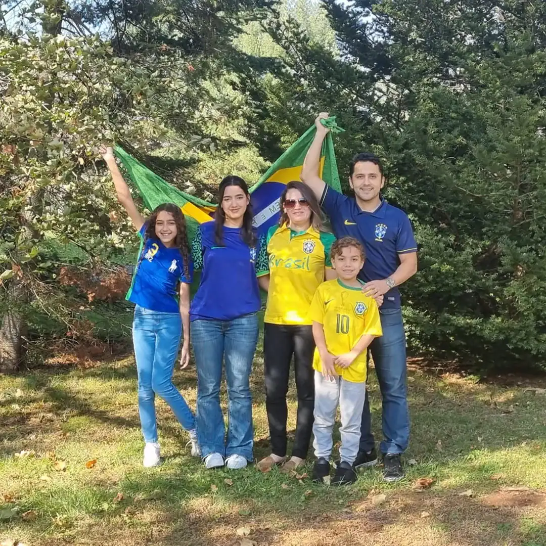 Família com bandeira do Brasil, celebrando o orgulho nacional ao ar livre.